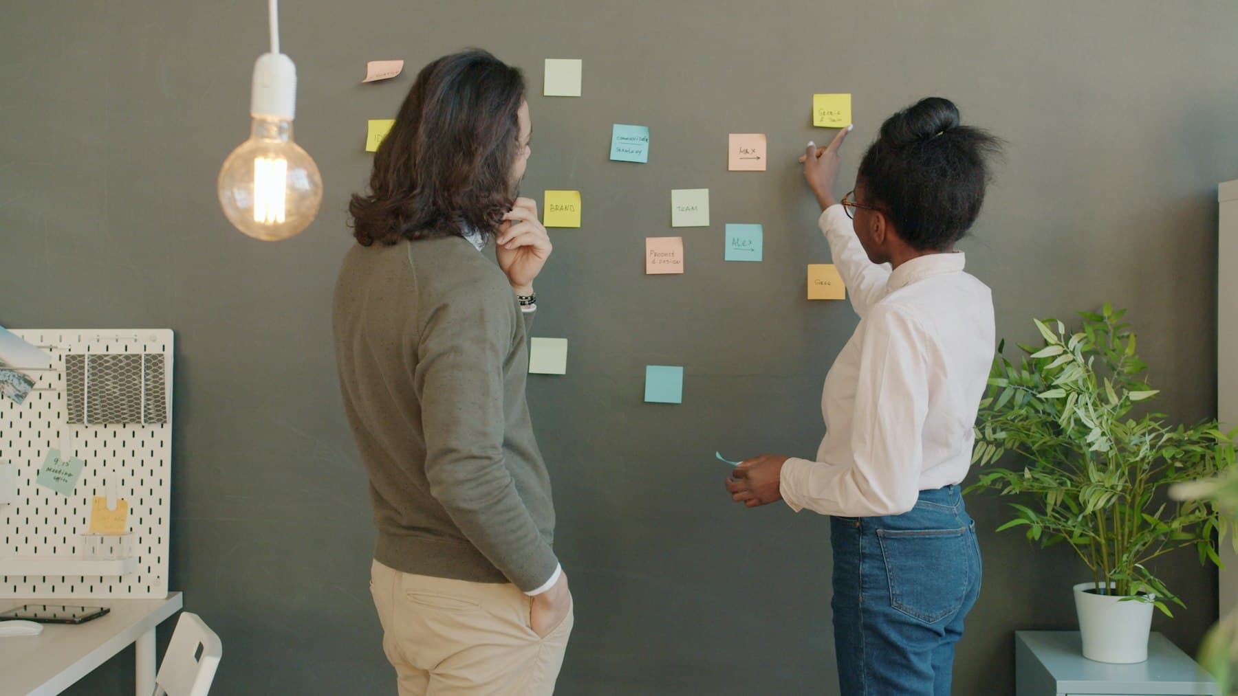 Two people brainstorming with sticky notes on a wall
