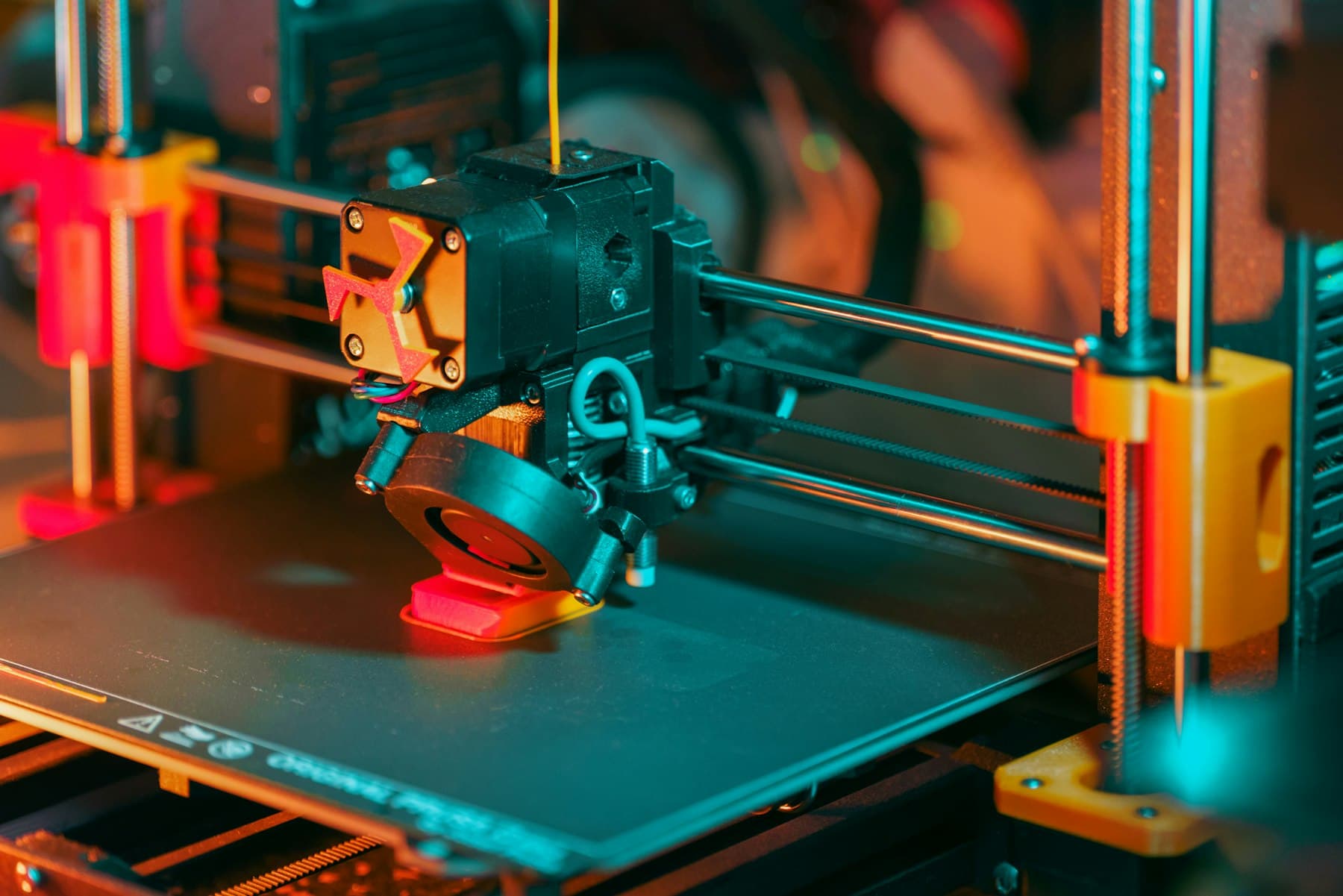 A 3D printer creating a red object with yellow filament