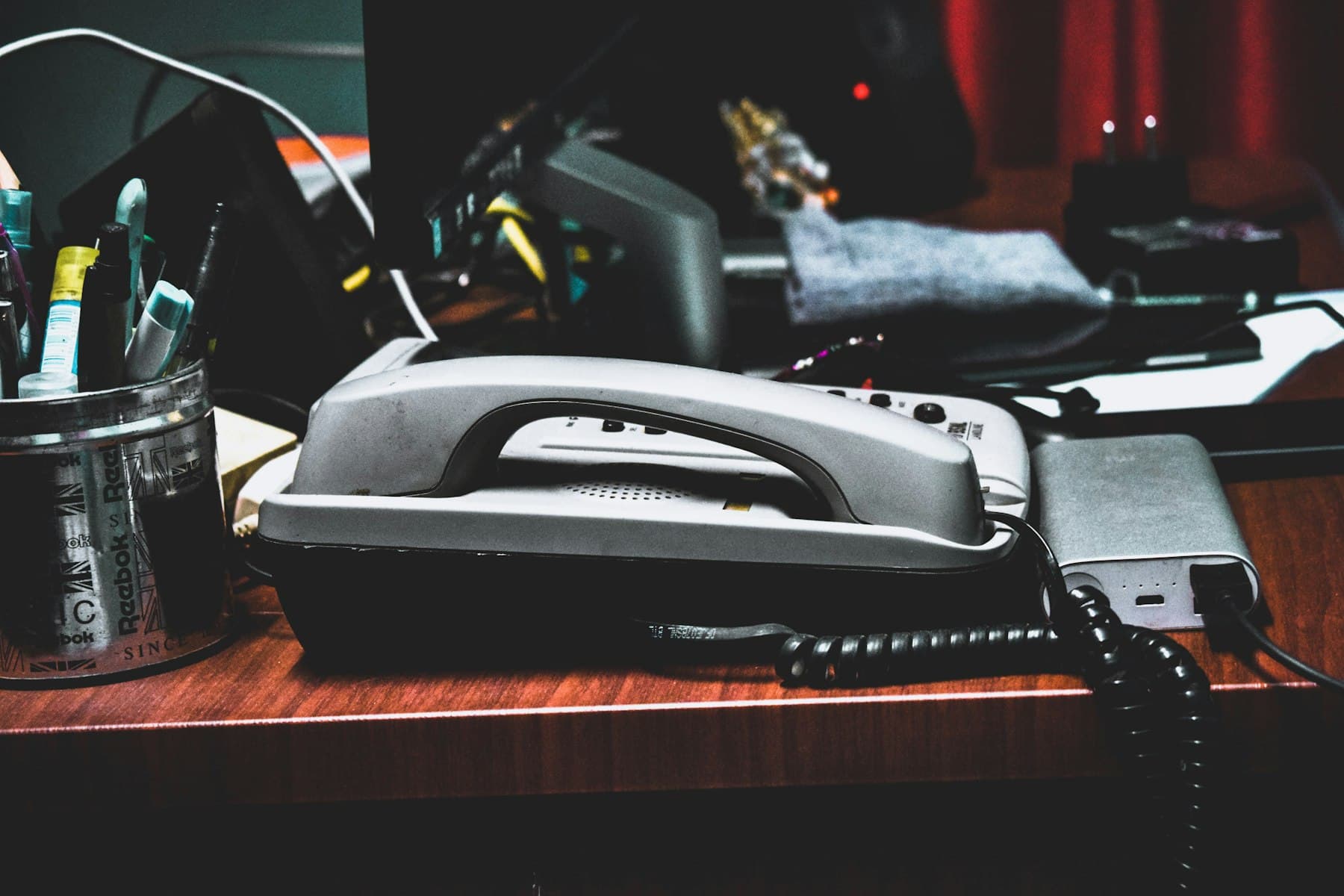 A desk with a phone, pencils, pens, and other office supplies