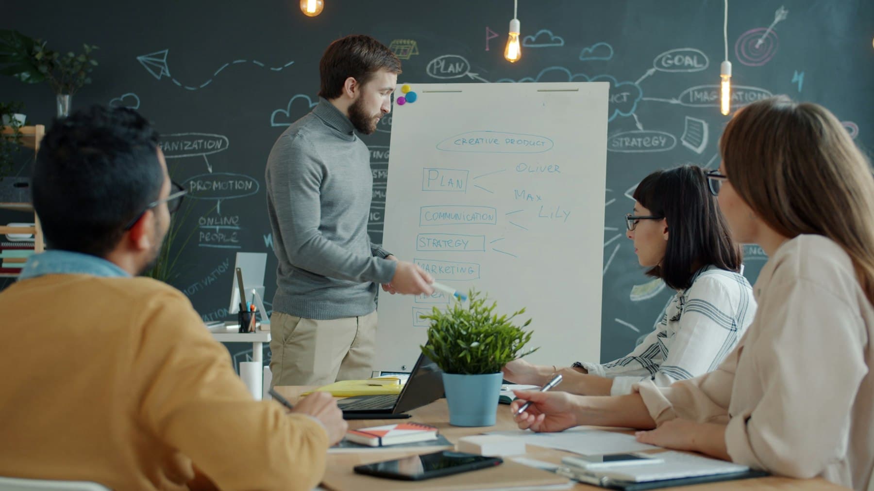 Office worker presenting a marketing strategy on a whiteboard to colleagues