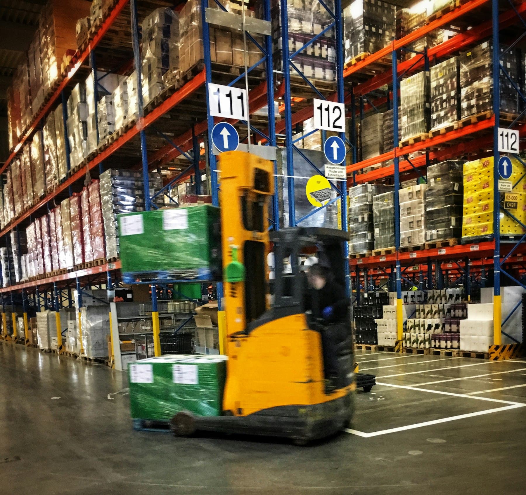 A forklift driving through a warehouse filled with pallets