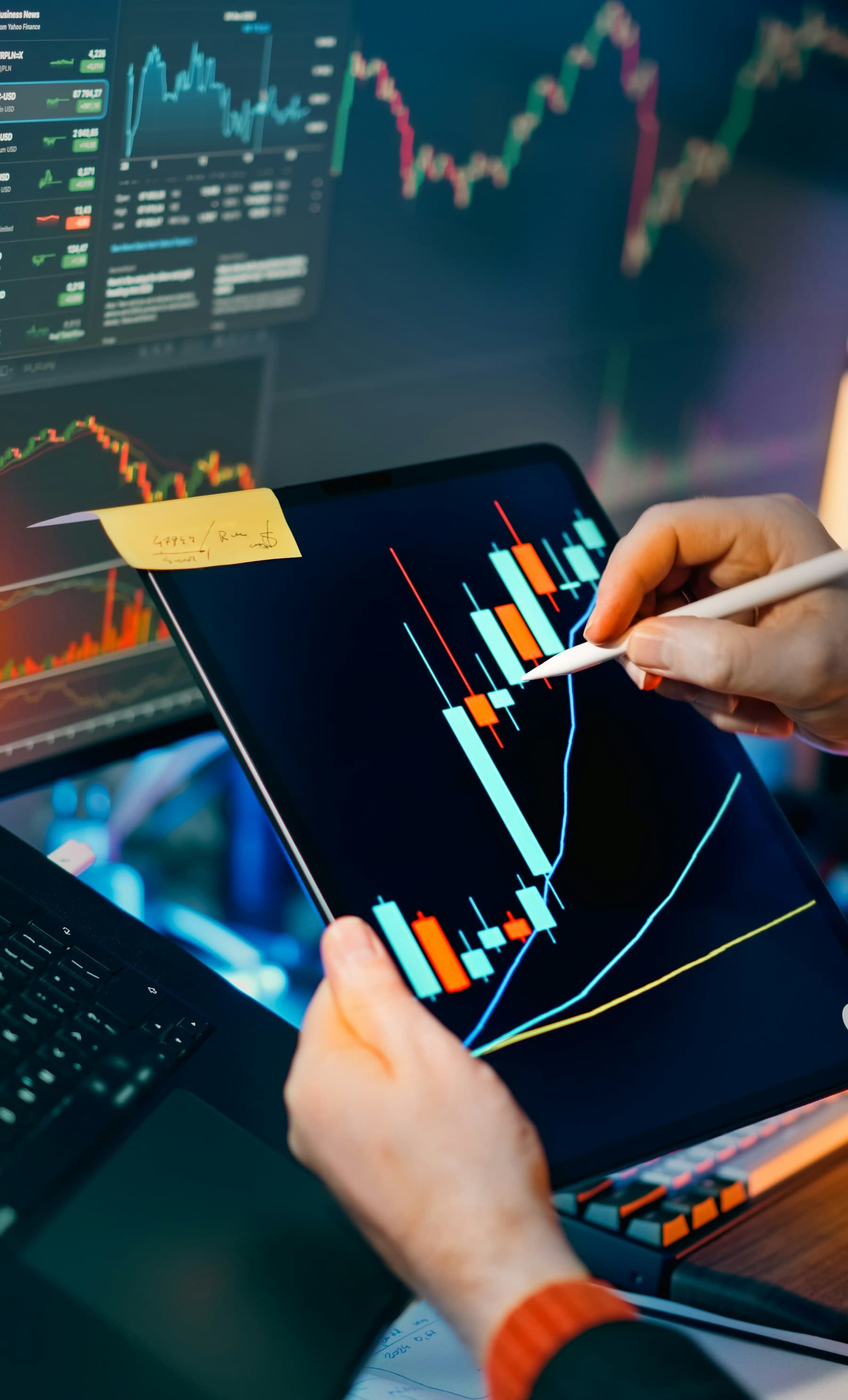 Trader analyzing stock market charts on a tablet and monitor